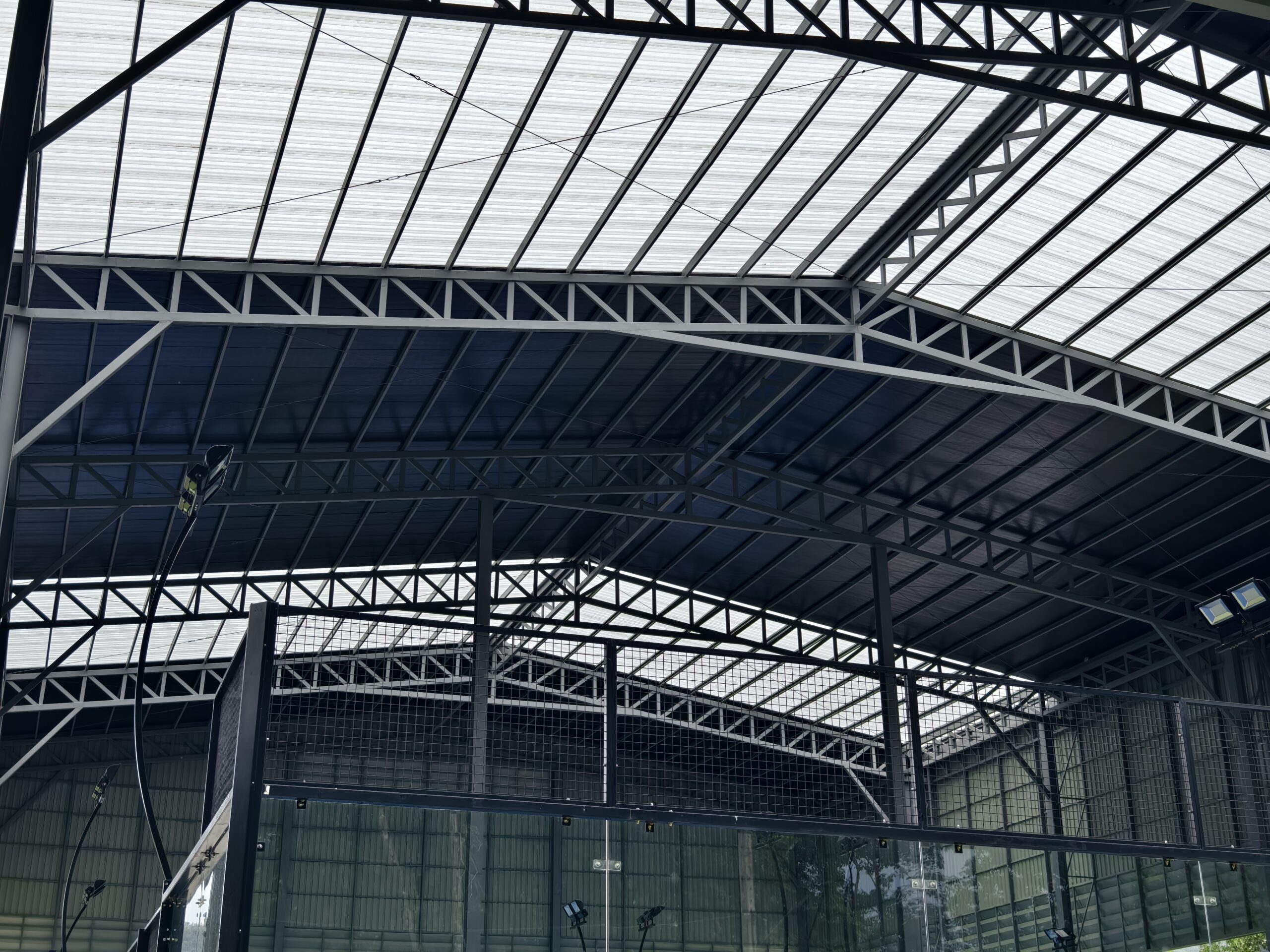 A large building with metal roof against a cloudy sky.